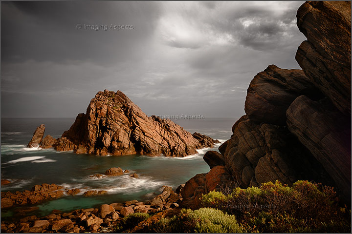 Clearing storm lights up the rocky shoreline at Sugarloaf Rock, Cape Naturaliste, Western Australia.