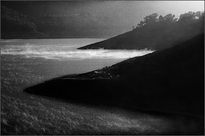 Early morning fog lifts along a section of Eildon Dam during drought — Lake Eildon National Park, Victoria.