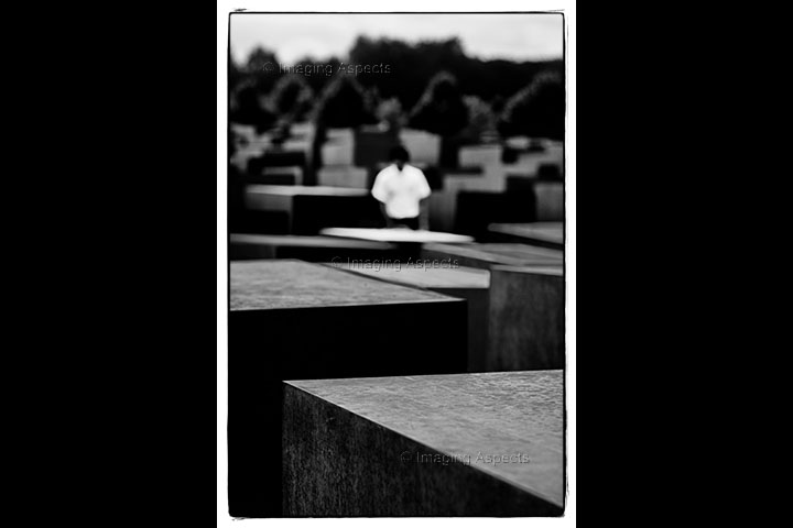 An out of focus man stands in the middle of the Memorial to the Murdered Jews of Europe in Berlin, Germany.