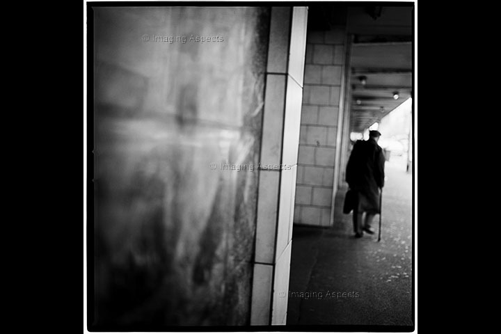 Old man with walking stick walks away from Spencer Street Railway Station (now Southern Cross Station) in Melbourne, Australia.